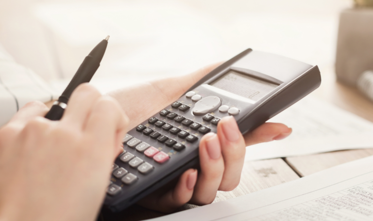 Close-up of hands using a calculator and reviewing financial documents, symbolizing the process of calculating child support payments in Ontario.