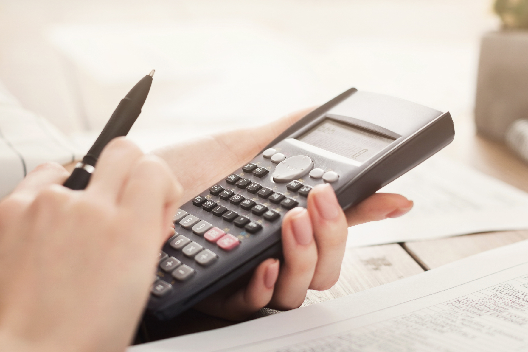 Close-up of hands using a calculator and reviewing financial documents, symbolizing the process of calculating child support payments in Ontario.