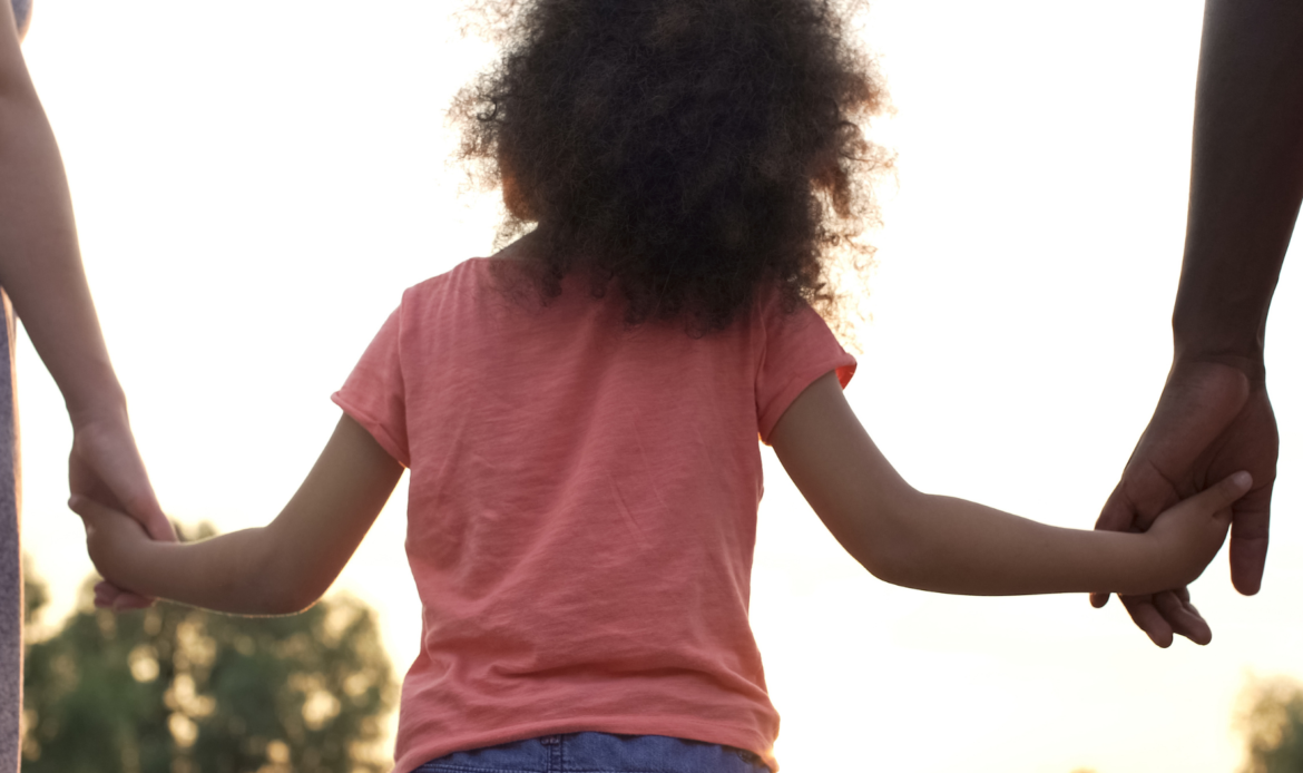 A child holding hands with both parents, symbolizing shared financial responsibility and child support in Ontario.