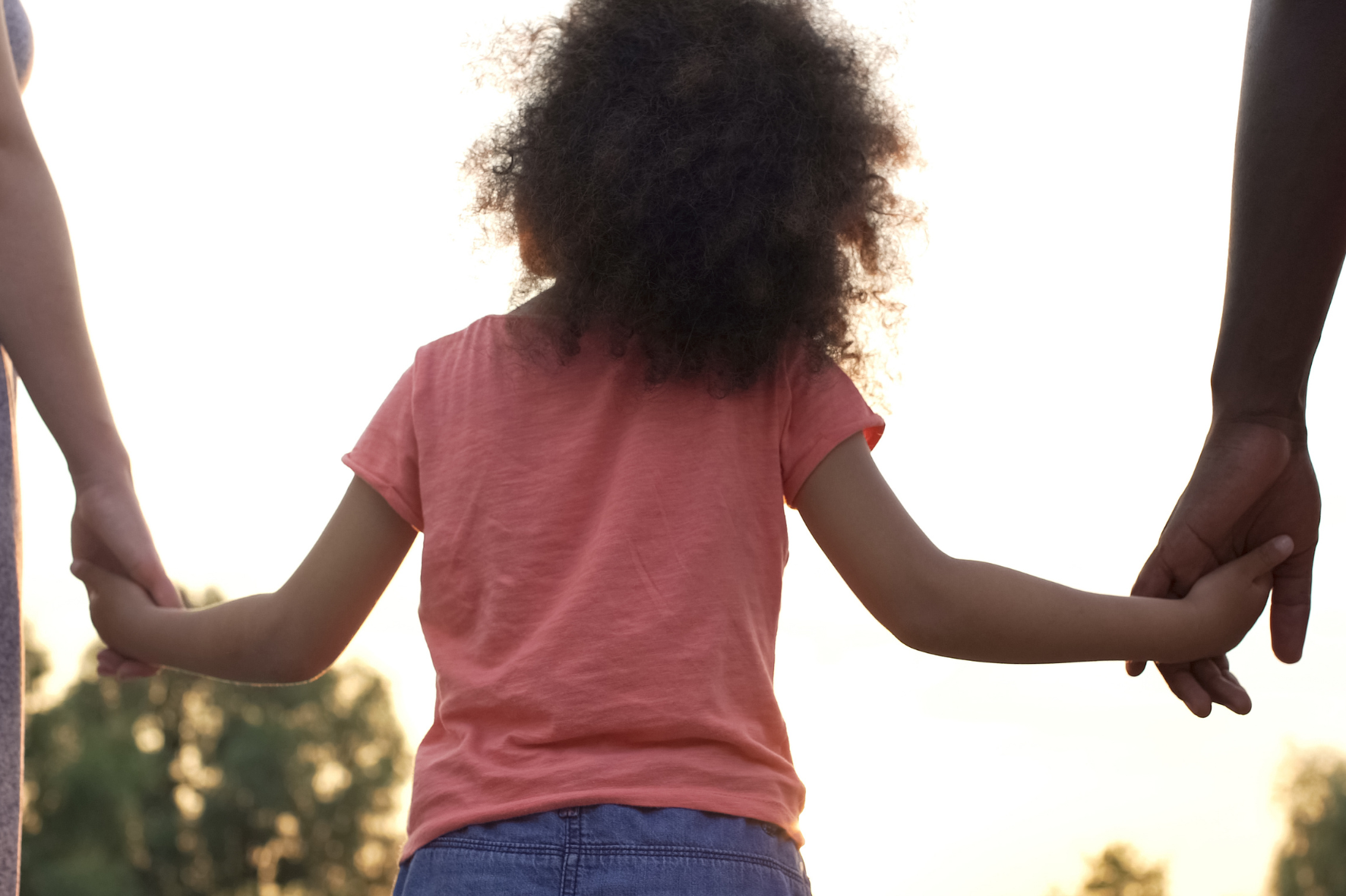 A child holding hands with both parents, symbolizing shared financial responsibility and child support in Ontario.