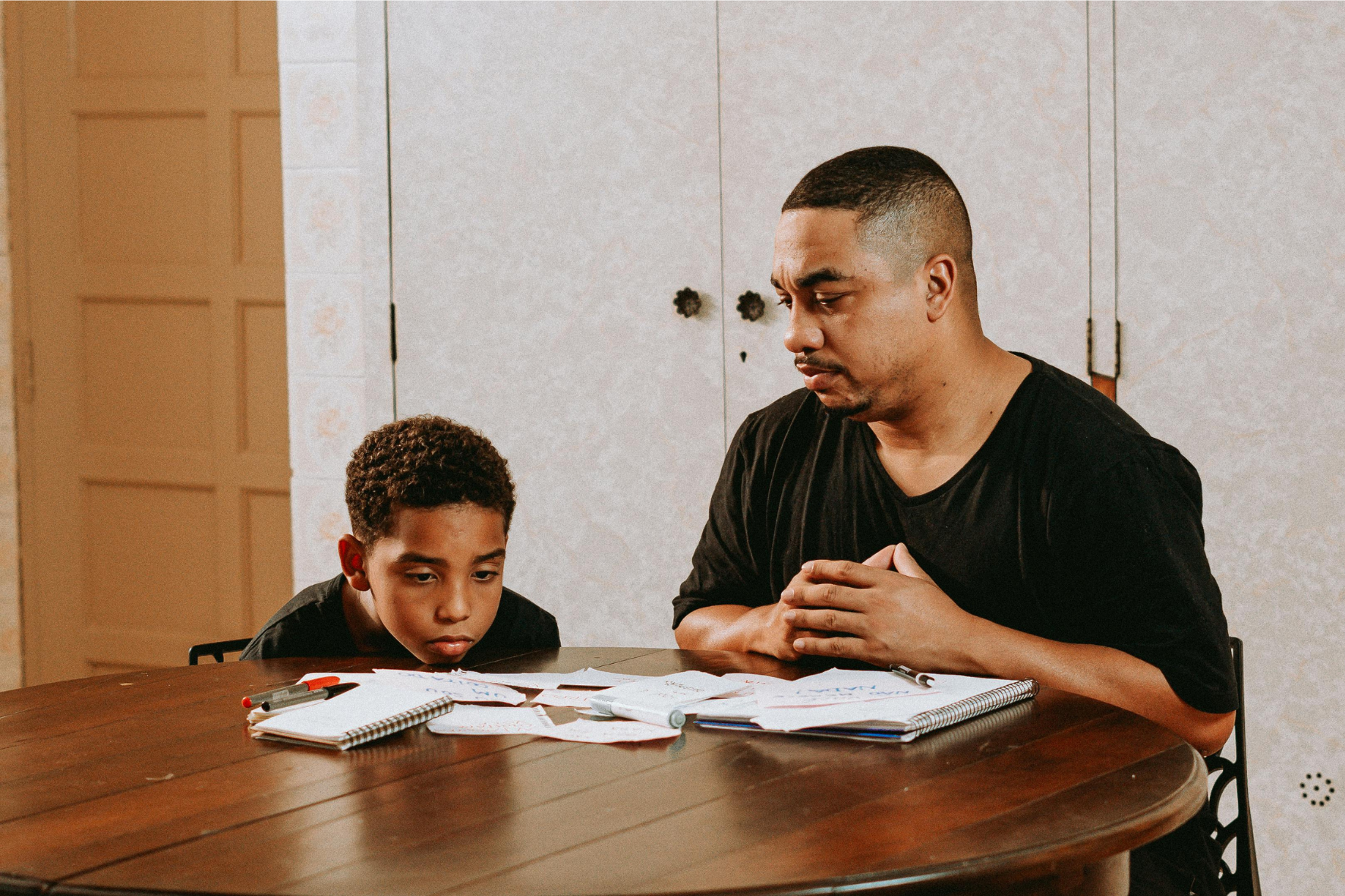 A father and son looking at financial documents, symbolizing the challenges of child support payments and financial responsibilities in Canada.