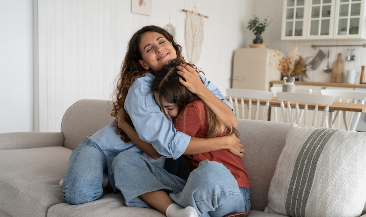 Mother and daughter embracing on a couch, symbolizing emotional support and financial stability provided through child support.