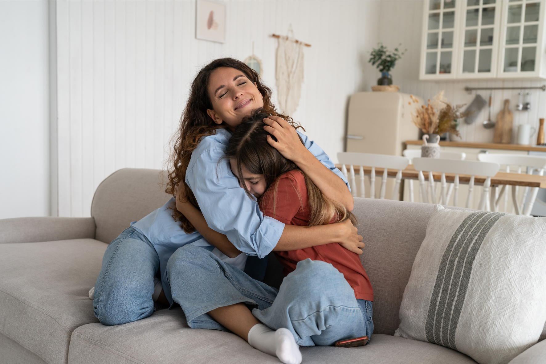 Mother and daughter embracing on a couch, symbolizing emotional support and financial stability provided through child support.