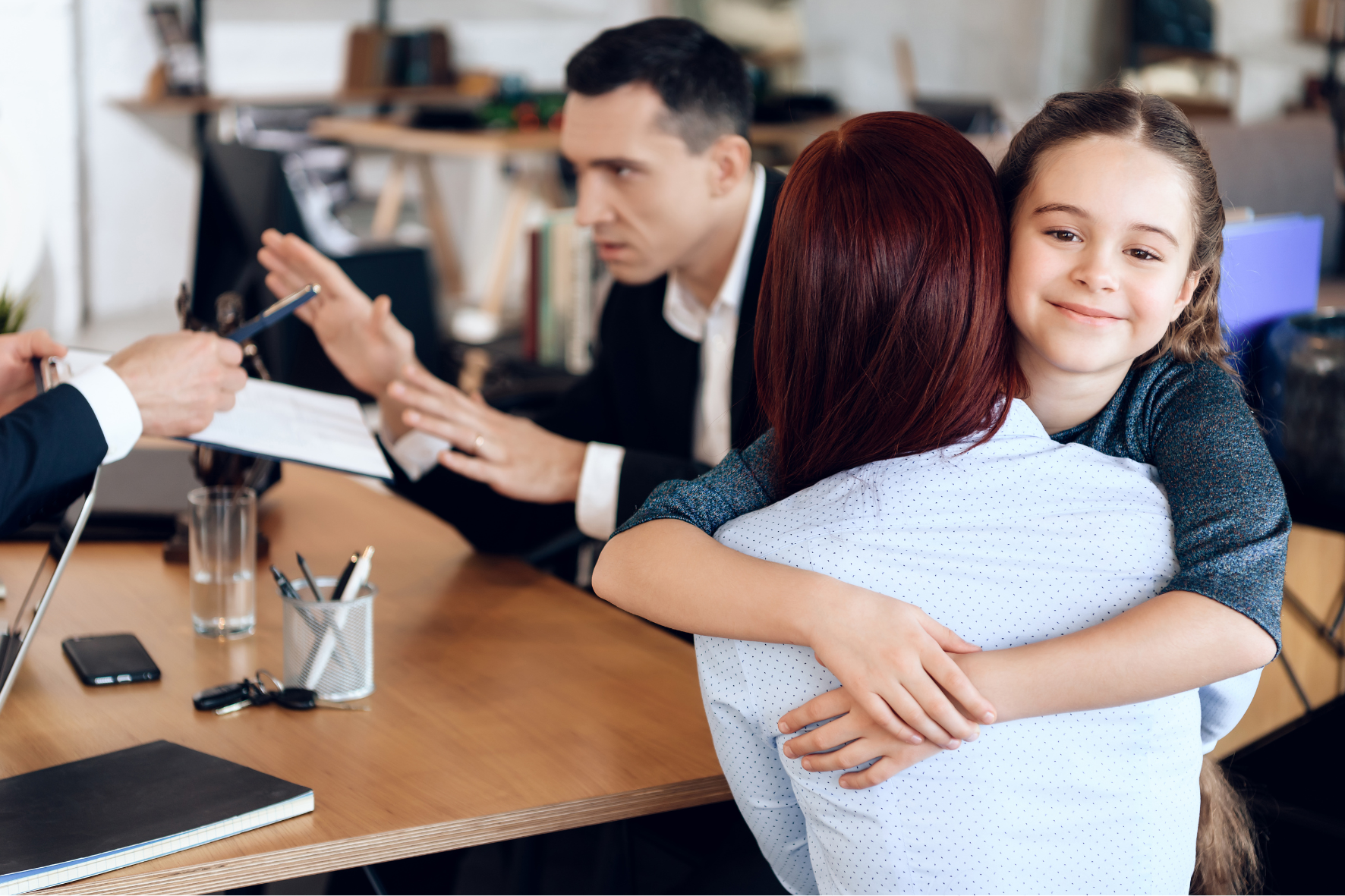 A mother hugging her smiling daughter during a custody discussion, while a lawyer mediates between parents in an Ontario child custody case.