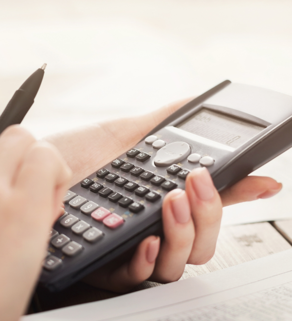 Close-up of hands using a calculator and reviewing financial documents, symbolizing the process of calculating child support payments in Ontario.