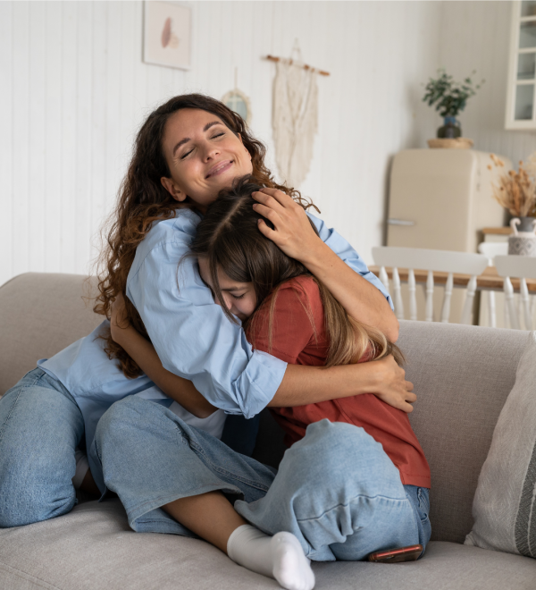 Mother and daughter embracing on a couch, symbolizing emotional support and financial stability provided through child support.